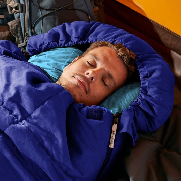 A man sleeping in a blue Silentnight Adult Sleeping Bag whilst camping