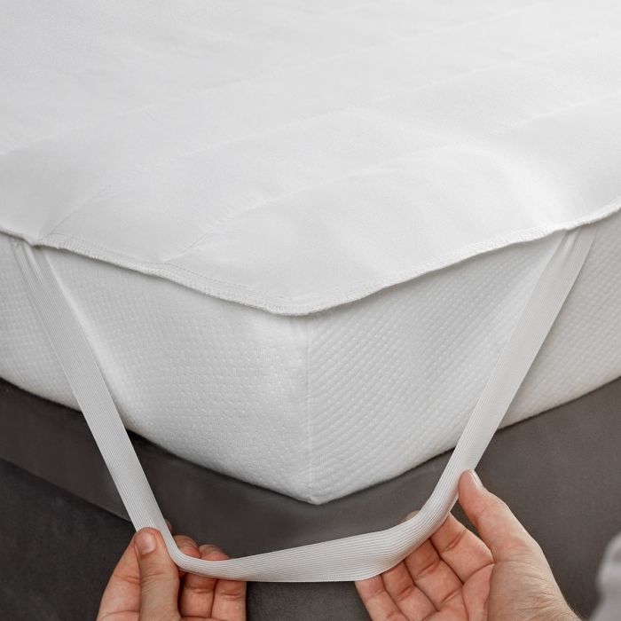 A person demonstrating how to attach the Silentnight Anti-Allergy Mattress Protector to a mattress